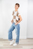 A woman modeling a brown and cream checkered short-sleeve knit top and jeans.