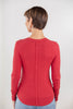 A woman shown from the back wearing a fitted long-sleeve red top with a vertical seam down the center back.