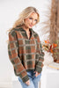 A woman wearing a long-sleeve quarter-zip knit sweater with a brown, green, and beige plaid pattern, paired with blue jeans.