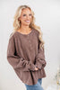 A woman wearing an oversized brown waffle knit henley top.