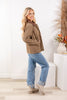 A woman modeling a tan corduroy-like button-up jacket with a brown collar, worn with blue jeans.