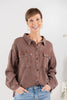 A woman wearing a brown waffle knit button-up shirt with chest pockets.