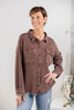 A woman wearing a brown waffle knit button-up shirt with chest pockets and blue jeans.