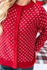 A close-up of a woman wearing a red knit cardigan sweater with a white Nordic-style snowflake pattern and matching red buttons.
