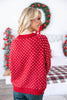 A woman wearing a red Christmas sweater with a white snowflake pattern, photographed from behind.