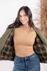 A woman modeling a olive green corduroy-like button-up jacket with a black and yellow plaid lining, worn with blue jeans.
