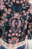 Close-up of a black knit sweater featuring a detailed floral and paisley pattern in pink, teal, and white, with blue and white rhinestone embellishments at the center.