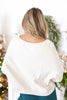 A woman viewed from behind wearing a cream-colored, oversized crewneck sweatshirt.