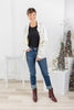 A woman modeling a light beige button-up jacket over a black top, blue jeans, and dark brown ankle boots.