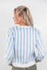A woman shown from the back wearing a light blue and white vertically striped long-sleeve knit top, paired with olive green pants, against a plain white studio background.