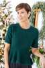 A woman wearing a dark green short-sleeve knit top with a peplum hem.