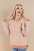 A woman with long blonde hair wearing a peach and white houndstooth patterned sweater, posing against a solid beige background.