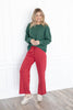A woman wearing a dark green ribbed knit long-sleeve top and red drawstring pants.