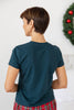 A woman viewed from behind wearing a dark teal short-sleeve t-shirt and red plaid pajama pants.
