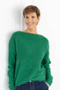 A woman wearing a bright green knit sweater and navy pinstriped pants.