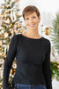 A woman wearing a black ribbed knit long-sleeve boat-neck sweater.
