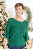 A woman wearing a green knit sweater with three-quarter sleeves.