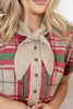 A close up of a woman wearing a short-sleeve knit cardigan with a red, green, and beige plaid pattern and a knotted tie neckline.