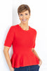A woman wearing a bright red short-sleeve ribbed knit top and navy pinstriped pants.