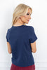 A woman is shown from the back wearing a navy blue short-sleeve t-shirt.