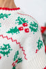 Close up of a knit sweater with a Christmas holly and berry pattern in green, red, and white.