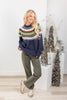 Woman wearing navy blue knit sweater with a colorful Fair Isle yoke pattern in green, orange, white, and blue with olive denim.