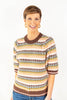 A woman modeling a short-sleeve knit sweater with horizontal multicolor stripes in brown, cream, yellow, pink, and sage, paired with blue jeans.