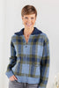 A woman wearing a blue and green plaid zip-up sweater jacket with a navy blue collar, paired with gray jeans.