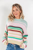 A woman wearing a pastel striped knit sweater with horizontal bands of mint green, pink, beige, and burgundy, paired with blue jeans, against a plain light gray background.