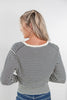 A woman viewed from behind wearing a black and white horizontally striped long-sleeve cardigan top with a cream-colored crew neck, paired with blue jeans, against a plain white background.