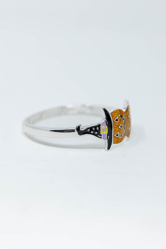 A silver bracelet featuring a witch hat and orange pumpkin topper with small purple and yellow accents, set against a plain white background.