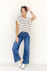 Woman wearing a striped shirt and blue jeans against a white background
