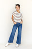 Woman wearing a striped sweater and blue jeans on a white background