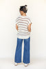 Person wearing a striped shirt and blue jeans on a white background