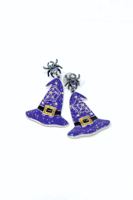 A pair of Halloween-themed dangle earrings featuring purple witch hats with silver glitter details, black belts, and small silver spider charms at the top, shown on a plain white background.