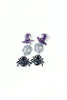 Three pairs of Halloween-themed stud earrings on a white background: purple witch hats, silver sugar skulls, and black spiders.