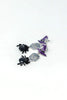 A pair of silver-toned dangle earrings featuring black spider charms and purple witch hats with glittery details, displayed on a clean white background.