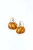 A pair of dangle earrings shaped like small orange and yellow striped pumpkins, featuring gold-tone wire stems and clear rhinestone accents, set against a plain white background.