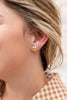 A close-up of a woman's ear wearing a small orange and white enamel candy corn stud earring.