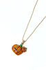 A gold chain necklace featuring a glittery orange pumpkin pendant with a carved jack-o'-lantern face and a small matching pumpkin charm, shown on a plain white background.
