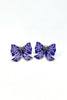 A pair of gothic-style bow earrings featuring deep purple enamel, white spiderweb patterns, and silver-tone metal details with small black rhinestones at the center, shown on a plain white background.