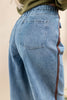 Woman shown from the back wearing blue jeans with a brown side stripe.